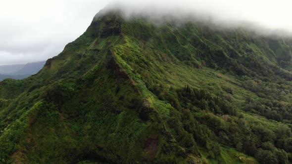 Drone rising up into the rain clouds while looking at the majestic mountain ridge in hawaii