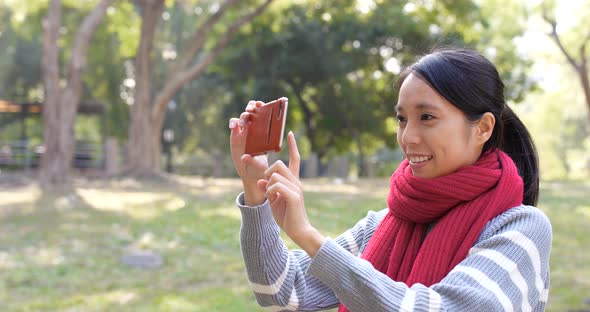 Woman using cellphone for taking photo in park