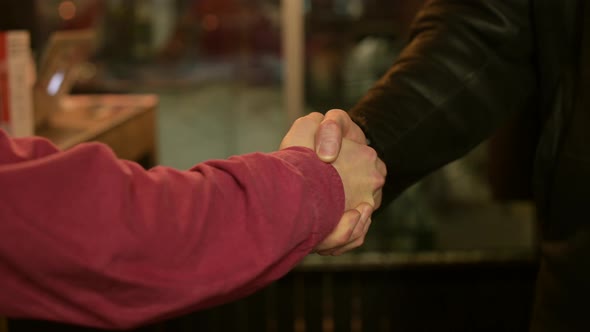 male handshake in a dark room of a smoky bar