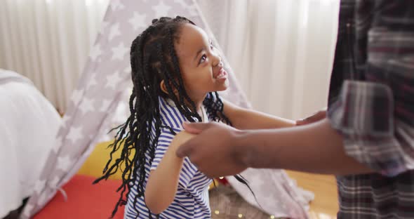 Happy african american father and daughter dancing and having fun at home