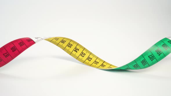 Twisted bright multi-colored centimeter measuring tape on a white background