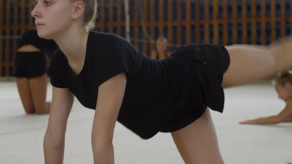 Teenage Girl Stretching Legs in Gym