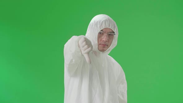 Asian Male Wearing Protective Uniform Ppe And Showing Thumbs Down, Unlike In Green Screen Studio