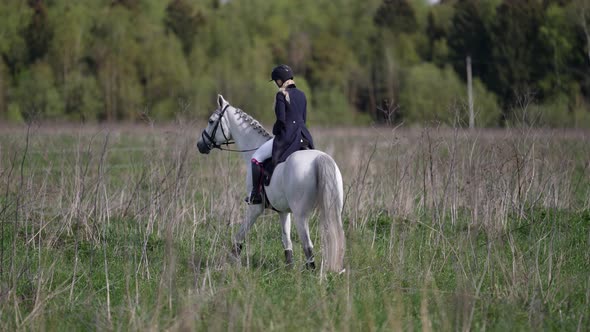 Graceful Female Jockey on White Horse on Field at Summer Day Horse Riding Hobby