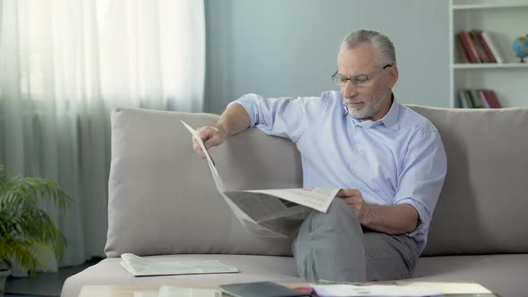 Old Male Sitting on Sofa and Reading Newspaper, Press and News, Rest Time