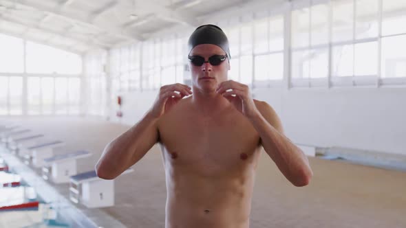 Swimmer taking off his pool goggles and looking at camera