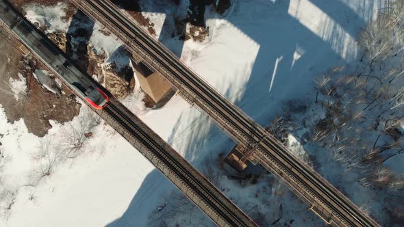 Aerial Shot Top Shot of a Train Crossing a Bridge Over the Mountain River in Sunny Winter Day.