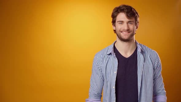 Positive Smiling Young Man Pointing to Copy Space for Advertising Yellow Background