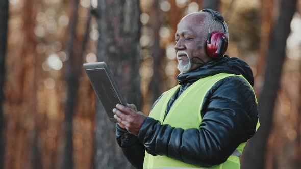 Closeup Elderly Forestry Engineer Enters Data Into Logging Tablet Reforestation of Woodland Serious