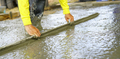 Construction worker leveling wet concrete floor with a trowel at construction site. Construction - PhotoDune Item for Sale