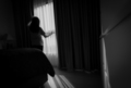Rear view of woman holding curtain and looking out of glass window. Depressed woman from lock down  - PhotoDune Item for Sale