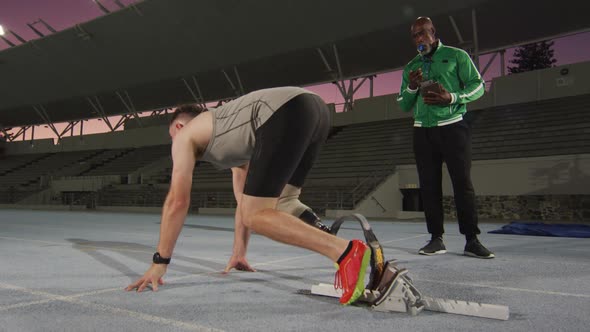 Diverse male coach and disabled male athlete with running blade getting ready to start a run