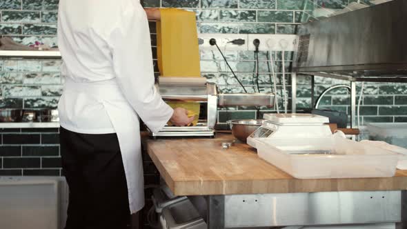 Chef Making Spaghetti Noodles and Lasagne Dough with Pasta Machine on Kitchen Table with Some