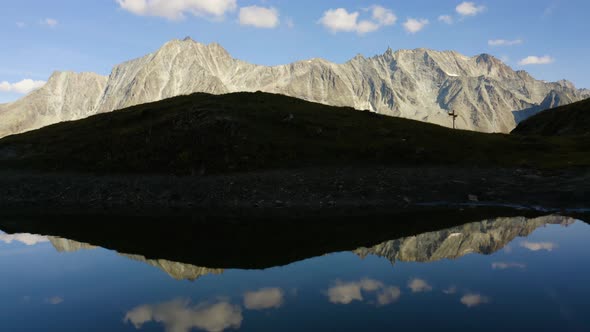 Flying low over perfect mirror lake with high mountain peaks in the backgroundAutumn colors in Arol