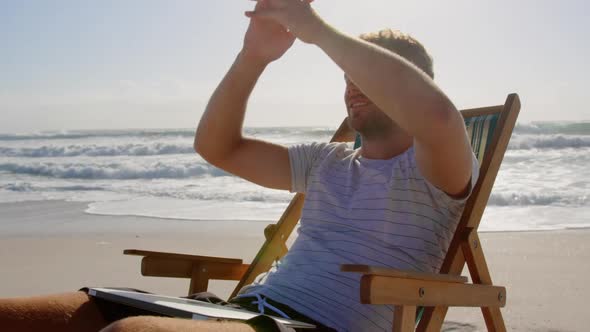 Man with hands behind head relaxing on sun lounger at beach 4k