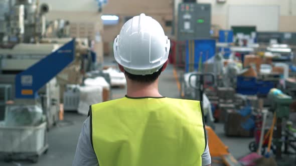 Factory Worker with Safety Hard Hat Walking Through Industrial Facilities