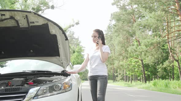 Beauitful Woman Looking Under the Hood of Her Broken Car on Countryside Road