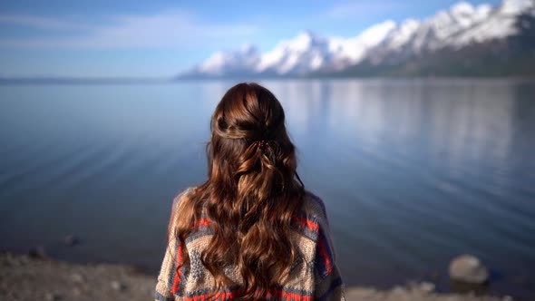 Amazing view a young attractive brunette girl standing in front of the water looking in the distance