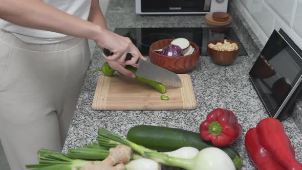 Girl Pours Green Chili Pepper Into A Wooden Bowl With Slices Of Eggplant