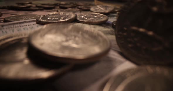 Many Coins Fall on Dollar Bills Closeup
