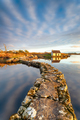 An old stone jetty across a lake leading to a small cottage - PhotoDune Item for Sale