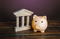 Piggy bank near the state building. Savings deposit in the bank. - PhotoDune Item for Sale