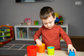 A cute little toddler boy of two years old sits at a children's table and plays  - PhotoDune Item for Sale