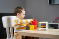 A cute little toddler boy of two years old sits at a children's table and plays with educational toy - PhotoDune Item for Sale