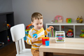 A cute little toddler boy of two years old sits at a children's table and plays with educational toy - PhotoDune Item for Sale