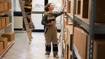et scanner, verifying barcodes of products in packages. Female worker analyzing boxes with cargo goods in storage room depot.