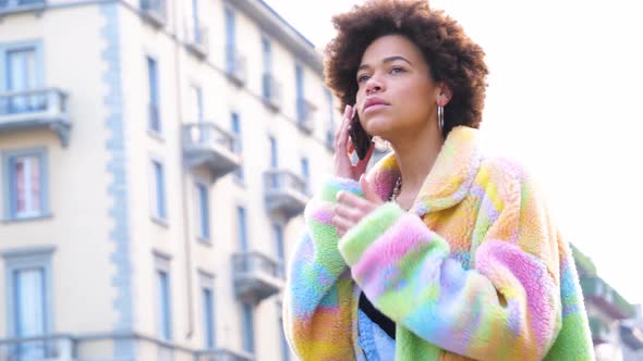 Young beautiful curly hair black woman outdoor in the city calling with smartphone