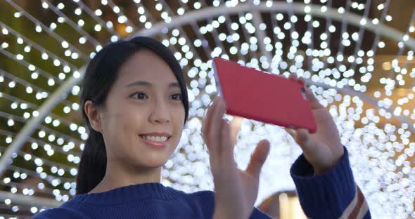 Woman use of the phone for take photo with the christmas decoration at night