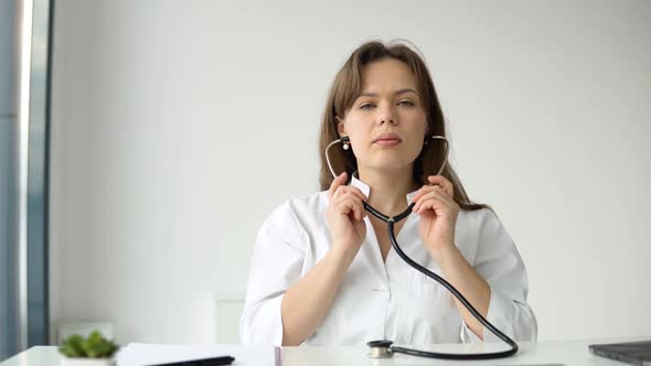 Happy Young Caucasian Woman Doctor Wearing White Medical Coat and Stethoscope Looking at Camera