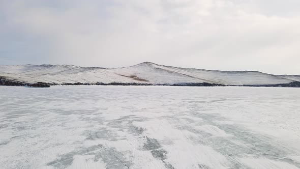 Baikal Lake Landscape with Cracked Frozen Ice Surface Covered with Snow in Winter