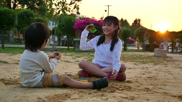 Asian Children Playing Sand In Playground Under Sunset