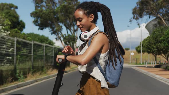 African american woman on scooter looking at smartwatch