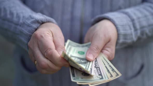 Elderly Woman Holds and Counts Cash in Arms