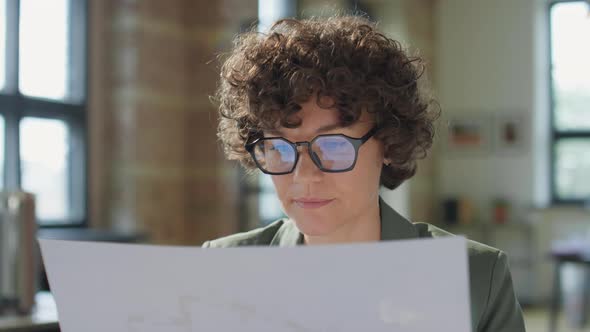 Female Architect Reading Paper in Office