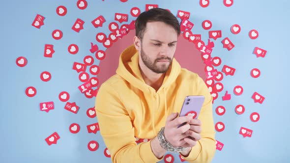 Handsome Caucasian Guy in Casual Clothes Uses a Smartphone Among Many Likes on a Blue Background