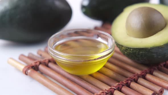 Oil and Slice of Avocado on Wooden Table