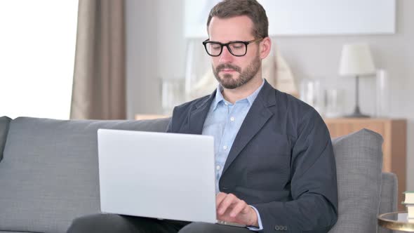 Sick Young Businessman Using Laptop Coughing at Home