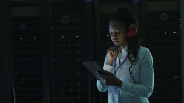 African american female computer technician using tablet working in business server room