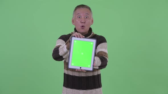 Happy Mature Japanese Man Showing Digital Tablet and Looking Surprised