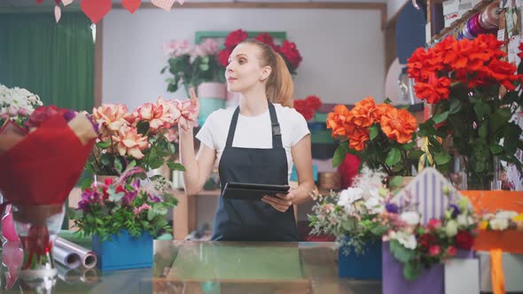 Botany and Working with Plants Florist Woman Takes Inventory in a Flower Shop a Female Uses a Screen