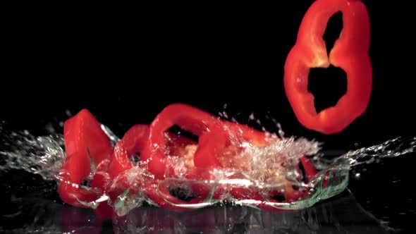 Super Slow Motion Pieces of Red Sweet Pepper Fall Into the Water with Splashes