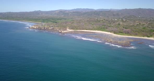 Aerial drone view of the beach, rocks and tide pools in Playa Palada, Guiones, Nosara, Costa Rica