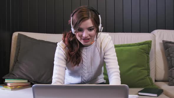 Young Woman Wears Headset Conference Calling On Laptop Talks With Online Teacher Studying