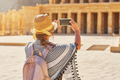Tourist woman taking photo od ruins Mortuary Temple of Hatshepsut - PhotoDune Item for Sale