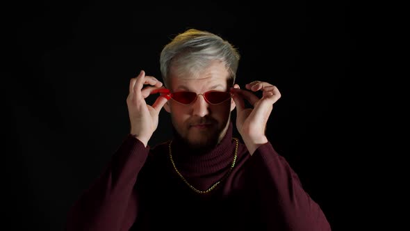 Portrait of Seductive Young Man in Trendy Stylish Clothes Wearing Red Sunglasses on Black Background