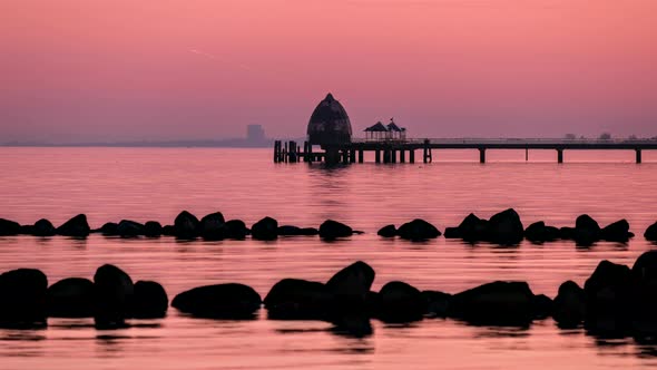 Beautiful Sunset above Calm Ocean with Pier, Diving Capsule and Stones (ProRes Timelapse)Day-to-nig